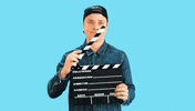 Video gif. A man shuts a movie clapper board and rolls his finger in a 360, saying, "That's a wrap!"