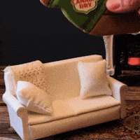 Sponsored gif. A hand places a lounging gingerbread man wearing a Canada Dry sweater onto a miniature couch. Text: "INTERNAL SLEIGHBELLS INTENSIFY"