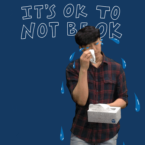 Video gif. Man wipes oversized cartoon tears from his eyes with tissue from a box that he tosses over his shoulder before walking away. Text on navy blue background, "It's ok to not be ok."