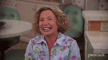 TV gif. Debra Jo Rupp as Kitty on That 70s Show squeezes her eyes shut and opens her mouth wide as she leans over and laughs uncontrollably.