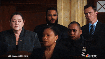 TV gif. Members of Law and Order sit close as they all react with a head nod or glance simultaneously. 