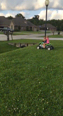 Video gif. Two kids are riding on a toy tractor and they ride straight into a ditch. They fall face first off the toy tractor, faceplanting into the grass and the tractor gently rocks on top of them from the momentum.