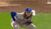Sports gif. In the middle of a baseball field, Scott Barlow of the Kansas City Royal squats down low, looking around, and biting his bottom lip. He then pops up and says, “oh wow.”