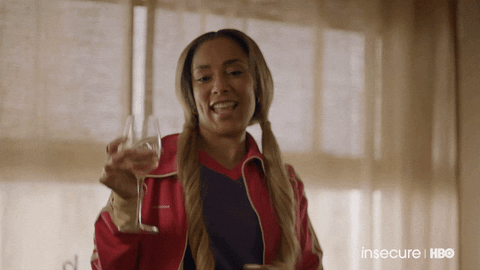 TV gif. Amanda Seales as Tiffany in Insecure holds a glass of wine and shimmies her shoulders, vibing.