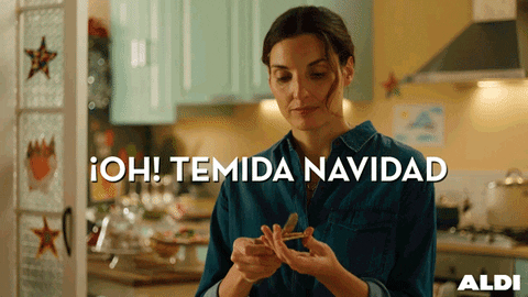 Video gif. Woman stands in her kitchen spreading peanut butter on a cracker, and suddenly the cracker breaks, surprising her. Text, “Oh! Temida Navidad.”