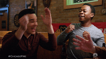TV gif. Daniel Kyri as Darren and Alberto Rosende as Blake in Chicago Fire turn and clap in excited celebration. 