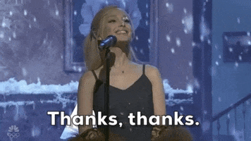 SNL gif. Ariana Grande finishes her performance on stage and she grins while looking up at the snow, that falls down around her and says, "Thanks, thanks," which also appears as text.
