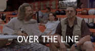 Movie gif. John Goodman as Walter in the Big Lebowski sitting at a bowling alley with The Dude, sitting up and shouting, "over the line."