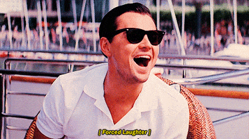 Movie gif. Leonardo DiCaprio as Jordan Belfort in The Wolf of Wall Street sits on a dock and sarcastically fake laughs in someone’s face. Text, “forced laughter.”