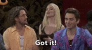 Video gif. Saturday Night Live castmember Mikey Day and guest host Ryan Gosling are dressed as Beavis and Butt-head for a sketch. Day and Gosling are sitting in the front row of a talk show audience. The two of them are staring straight ahead with goofy smiles on their faces. 