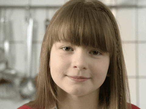 Video gif. Young girl putting two thumbs up right near her face an smiling wide with approval.