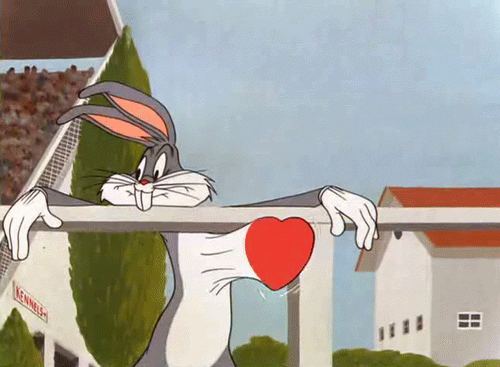 Cartoon gif. Bugs Bunny hangs his arms over the edge of a fence post and smiles while his heart literally beats out of his chest.