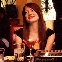 Movie gif. Emma Stone as Hannah in Crazy, Stupid, Love sits at a table in a restaurant, smiling and blushing as she turns away with a touch of embarrassment.
