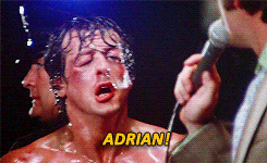 Movie gif. Sylvester Stallone as Rocky Balboa drips with sweat after a fight, approaches a man with a microphone and calls out "Adrian!" which appears as text.