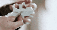 Video gif. Hands gently hold a small white angel figurine as if in reverence.