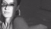 Music video gif. From Fletcher's video for "Sex With My Ex," black and white video zooms in on the face of a girl who looks to the side, seemingly annoyed, and then zooms in toward her breasts.