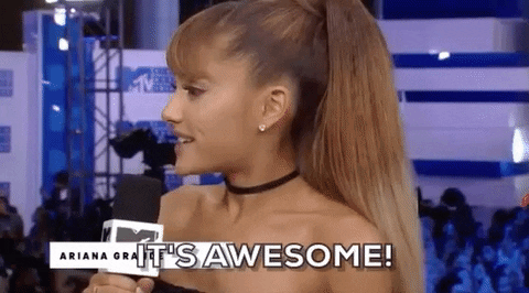Celebrity gif. Ariana Grande smiles and shrugs her shoulders, speaking into an MTV microphone, "It's awesome!" which appears as text.