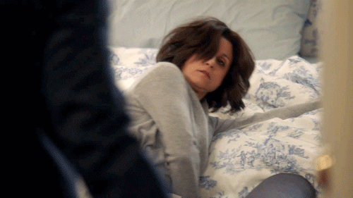 TV gif. Julia Louis-Dreyfus as Selina in Veep looks groggy as she sits up in bed with disheveled hair.