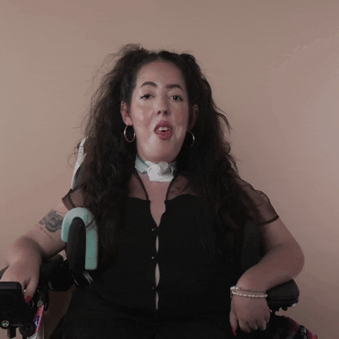 Reaction gif. A Disabled white woman with muscular dystrophy with wavy brown half up half down with two pigtails on top, seated in her motorized wheelchair, rolls her eyes all the way around.