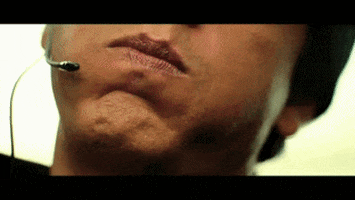 Celebrity gif. Close-up of Shahrukh Khan's mouth saying, "Boom" into his headset's microphone.