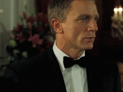 Movie gif. Daniel Craig as James Bond is clad in a black suit and bowtie but also wears a deadpan expression while saying bluntly, "Do I look like I give a damn?"