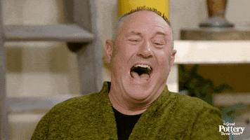 TV gif. Keith Brymer Jones, a judge on The Great Pottery Throw Down, laughs to the point of speechlessness, his mouth in a wide-open smile, as he points at something off screen. 