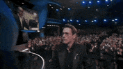 Oscars 2024 gif. In disbelief, Robert Downey Jr receives his Oscars trophy for Best Supporting Actor from Ke Huy Quan. He grabs the trophy with one hand and shakes hands firmly with Tim Robbins. 