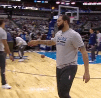 Sports gif. Deron Williams from the Dallas Mavericks walks up to a child on the sidelines and gives him a low high five after completing a successful run.