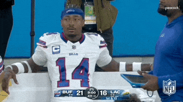 Sports gif. Stefon Diggs of the Buffalo Bills sits on the sidelines relaxing back in a bench as he looks up with wide eyes and mouth open like he's in shock or perhaps praying for a good outcome. 