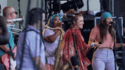 Celebrity gif. Singer Lauren Diagle celebrates with her band on stage, throwing her hands in the air and opening her mouth wide in excitement.