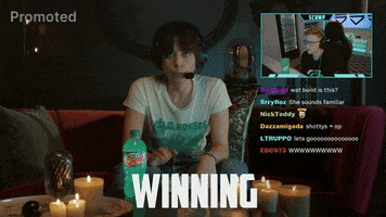 Sponsored gif. Aubrey Plaza wears a gamer headset and presses a key repeatedly on her keyboard with a Mountain Dew Baja Blast sitting next to it. She's in the middle of streaming with another gamer, whose video box is picture in picture on the top right while a bunch of comments pour in below it. She's locked in, unblinking as she repeatedly says, "Winning."