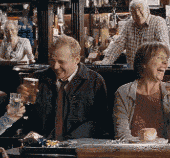 Movie gif. Simon Pegg as Shaun in Shaun of the Dead holds up his beer in a toast and winks.