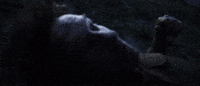 Movie gif. Thomas Kretschmann as Dr. Andre Mason in Discarnate lies on his back in the dark as his head wobbles and he looks disoriented.