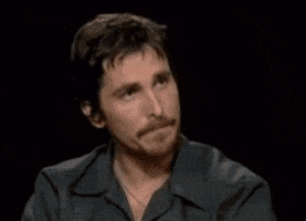 Muppets gif. Christian Bale presses in his lips and blankly nods at Kermit the Frog, who sits across from him and responds with a silent nod.