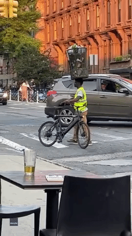 Man Balances Trashcan Atop Head While Cycling 