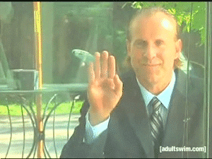 Video gif. Man with slicked back hair and dressed in a suit and tie waves mischievously through a window. A smirk plays upon his face as he stops waving, slowly spreads his fingers, and gives a thumbs up.