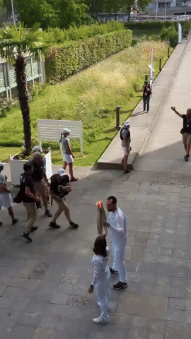 Olympic Flame Passed Between Cycling and Futsal Athletes Near Paris