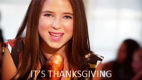 Holiday gif. Young girl sings passionately into a turkey leg. Text at the bottom reads, "It's Thanksgiving."