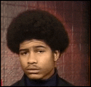 Video gif. Man with an afro is completely unamused, repeatedly shaking his head while staring straight at us.