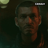 TV gif. Franck Gastambide on Validé subtly smiles evilly, but his face quickly drops into a menacing scowl. Red lighting glows off of his face, making him appear more intimidating.