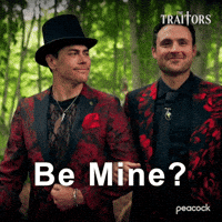 Sponsored gif. Traitors cast members Tom Sandoval and Dylan Efron, dressed in identical red and black patterned suit jackets, happily walk arm in arm through a forest. Text reads, “Be mine?”