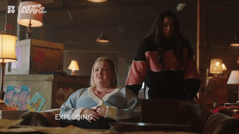 TV gif. Samantha Aucoin as Lilly in Astrid and Lilly Save the World tearfully says, "Exploding heads? It's only Tuesday," while Jana Morrison as Astrid rolls her eyes, crossing a leg over the couch.