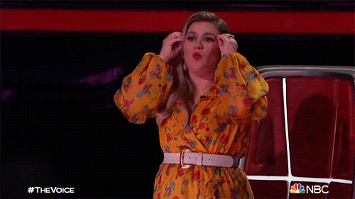 Reality TV gif. Kelly Clarkson as a coach on The Voice. She stands up from her seat and uses both hands to mime a mindblown expression, looking very impressed.