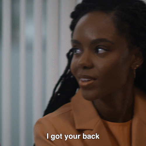 A woman is telling another woman, 'I got your back' and she replies, 'Thank you.'