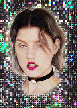 Video gif. A woman wearing a choker stares at us with half lidded eyes and her head twitches in rhythm with the background as it shakes and glimmers with sequins.