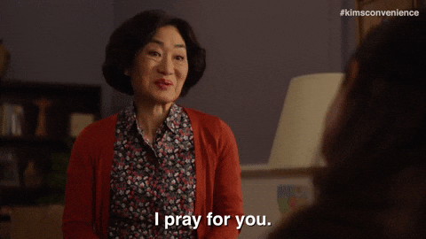 TV gif. Jean Yoon as Yong-mi Kim from Kim's Convenience bows slightly, a wry smile on her face, and says, "I will pray for you."