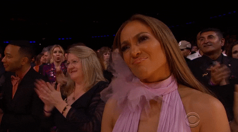 Celebrity gif. Jennifer Lopez during the Grammys. She looks kindly at the stage and scrunches her nose in compassion and pride as she claps after the performance.