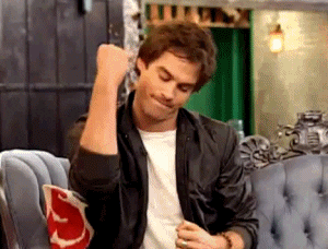 Celebrity gif. Ian Somerhalder, wearing a black leather jacket and sitting on a couch, bites his lip and pumps his fist as if to say "hell yeah."