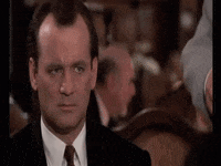 Movie gif. Bill Murray as Frank Cross in Scrooged darts his eyes around, confused.