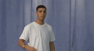 Celebrity gif. Young Drake leans backwards and pretends to pull out an imaginary gun from his pocket, almost like a cowboy in a standoff would. He says, “boom,” and lifts his hands up.